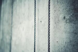 Gray concrete wall with twisted ropes showcasing industrial design and minimalism in modern architecture photo