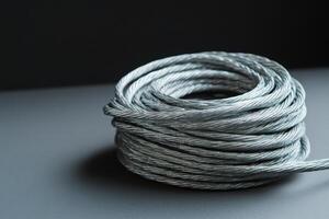High-quality metallic wire coil resting on a dark surface, showcasing its intricate texture and sheen under soft light photo
