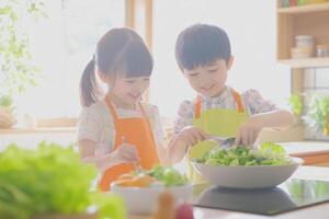 Kids engaging in healthy cooking activity while preparing fresh salad in a bright kitchen during the day photo