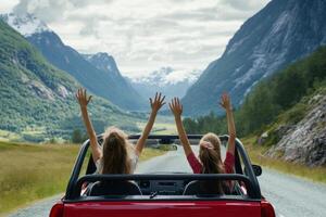 Two girls enjoy a joyful road trip with hands in the air in a scenic mountain landscape photo