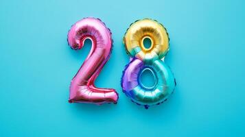 Colorful rainbow foil balloon with the number 28 on a vibrant blue background, ideal for birthdays and celebrations photo