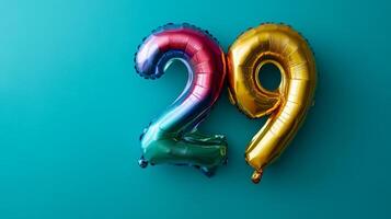 Vibrant rainbow foil balloon displaying the number twenty-nine on a blue background for a festive celebration photo