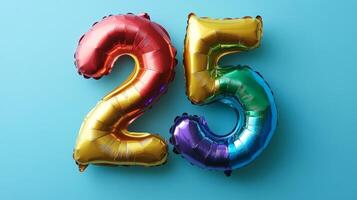 Colorful rainbow foil balloon number twenty five floats against a bright blue background for a celebratory occasion photo