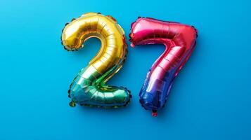 Bright rainbow foil balloon showcasing the number twenty-seven on a vibrant blue background for celebrations and events photo