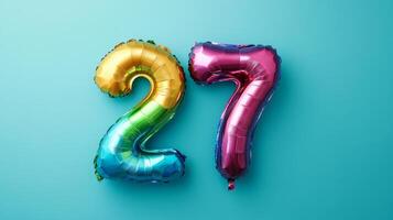 Colorful rainbow foil balloon displaying the number twenty-seven on a vibrant blue background, perfect for birthdays or celebrations photo