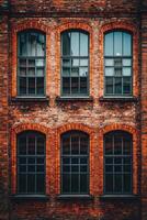 Vintage red-brick building facade featuring large windows in an urban setting during the day photo