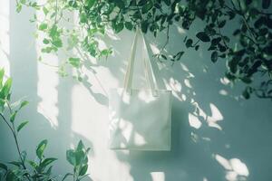 Minimalist canvas tote bag hanging serenely among lush green plants in soft natural light with blank space for design ideas photo