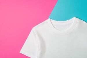 Minimalist styling of a folded white t-shirt showcasing clean lines on a vibrant pink and blue background in a studio setup photo