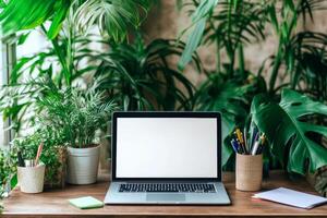 Minimalist workspace with a laptop on a desk surrounded by plants and stationery in daylight photo