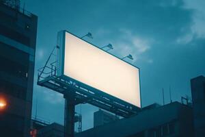 Large blank billboard on building facade illuminated by evening city lights with a blurred background creating a minimalist urban atmosphere photo