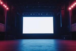 A large blank screen on stage in a concert hall with colorful lights in a dark setting ready for an event or presentation photo