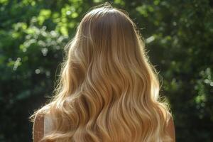 A woman admiring her long, shiny blonde hair illuminated by the golden hour sunlight in a lush, natural setting photo