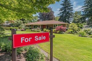 Bright red for sale sign in front of classic suburban home with well-kept lawn and gardens in a peaceful neighborhood photo