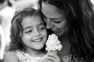 Mother and daughter share joyful ice cream moment outdoors during a sunny day in the park, creating sweet memories together photo