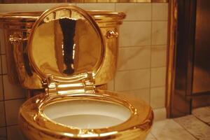 Golden toilet displayed in luxurious restroom interior with marble and shiny finishes photo
