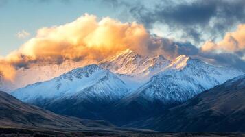 Majestic snow-covered mountains illuminated by golden hour light with dramatic clouds swirling above photo
