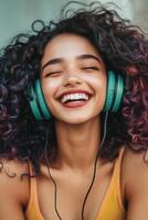 Beautiful young woman laughs joyfully while listening to music with headphones in vibrant street setting photo