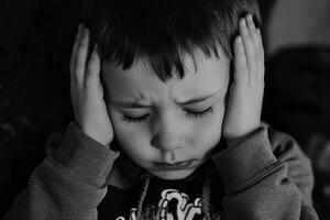 Child expressing distress by covering ears in a quiet indoor setting photo