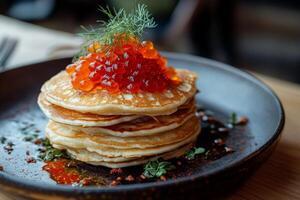 Delicious stack of pancakes topped with vibrant salmon roe served in a cozy breakfast setting photo