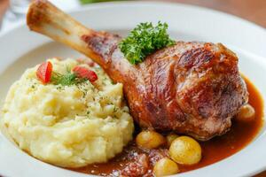 Delicious eisbahn pork knuckle served with creamy mashed potatoes and flavorful stewed cabbage in a cozy dining setting photo
