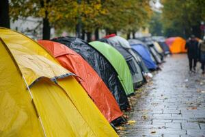 Tents lined up on a city street, forming a homeless encampment amid autumn weather and urban surroundings photo