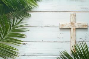 Wooden cross with palm leaves on a white wooden background symbolizing faith during Holy Week and religious observances photo
