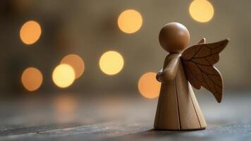 A wooden angel figure with delicate wings positioned against a blurred backdrop of warm bokeh lights in a cozy setting photo