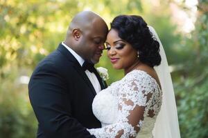 A beautiful curvy wedding couple embraces lovingly outdoors during a sunny afternoon in a lush garden setting photo
