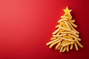 This festive display features cute french fries creatively stacked to resemble a Christmas tree, topped with a star, against a bright red backdrop photo