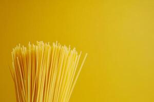 Fresh spaghetti prepared for a delightful meal against a bright yellow background with ample copy space for creative use photo
