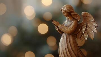 A beautiful wooden Christmas angel figurine in prayer set against a soft bokeh background, creating a warm holiday atmosphere photo