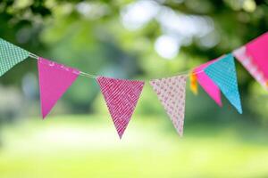 Vibrant bunting flags strung across a lively outdoor celebration in a sunlit park creating a festive atmosphere for attendees photo