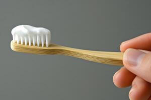 A hand holds a bamboo toothbrush with white toothpaste to promote eco-friendly oral hygiene practices photo