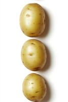 Five freshly washed raw potatoes arranged in a row on a clean surface ready for cooking or preparation photo