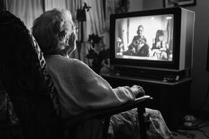 Grandmother with a disability enjoying a movie at home in a cozy setting during the evening photo
