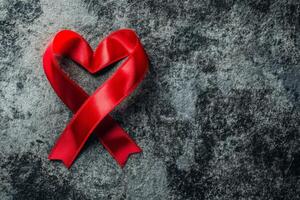 A beautifully arranged red ribbon in the shape of a heart on a textured dark background for decorative purposes or symbolism photo