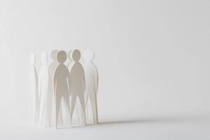 Group of cut-out paper figures standing together on a plain background photo
