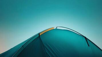 Camping tent silhouetted against a vibrant sky at twilight in a serene outdoor setting photo