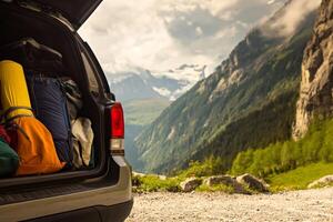 Scenic mountain view with open vehicle trunk displaying camping gear in summer photo