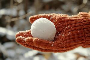 A hand holds a snowball tightly in a knitted glove during a serene winter moment surrounded by nature photo