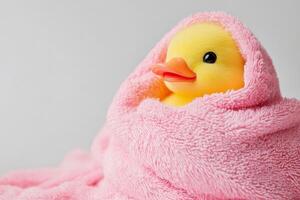 A cheerful rubber duck wrapped in a fluffy pink towel, perfect for playful bath time fun at home photo