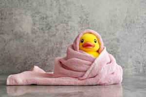 A cheerful rubber duck wrapped in a soft pink towel enjoying bath time fun in a cozy atmosphere photo