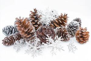 Snow-covered pinecones and delicate snowflakes arranged on a bright white background, capturing the essence of winter's beauty photo
