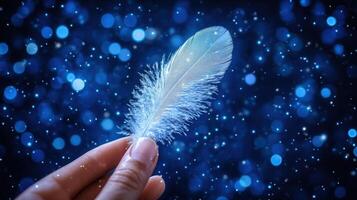 Woman's hand holding feather, magical bokeh background, fantasy, design photo