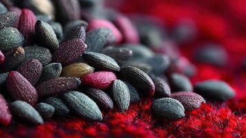 Pile of colorful sesame seeds on a vibrant red textured surface close up photo