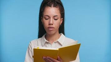 Thoughtful woman reading book and looking up on blue video