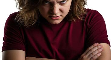 Angry young adult with brooding expression and arms crossed tightly photo