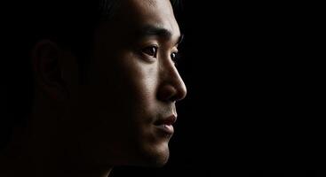 Asian man portrait in profile with dramatic lighting and dark background photo