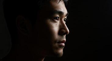 Dramatic portrait of a thoughtful Asian man in profile with intense gaze photo
