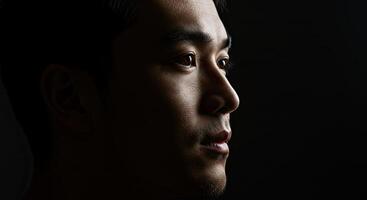 Dramatic side portrait of a young Asian man with strong facial features photo